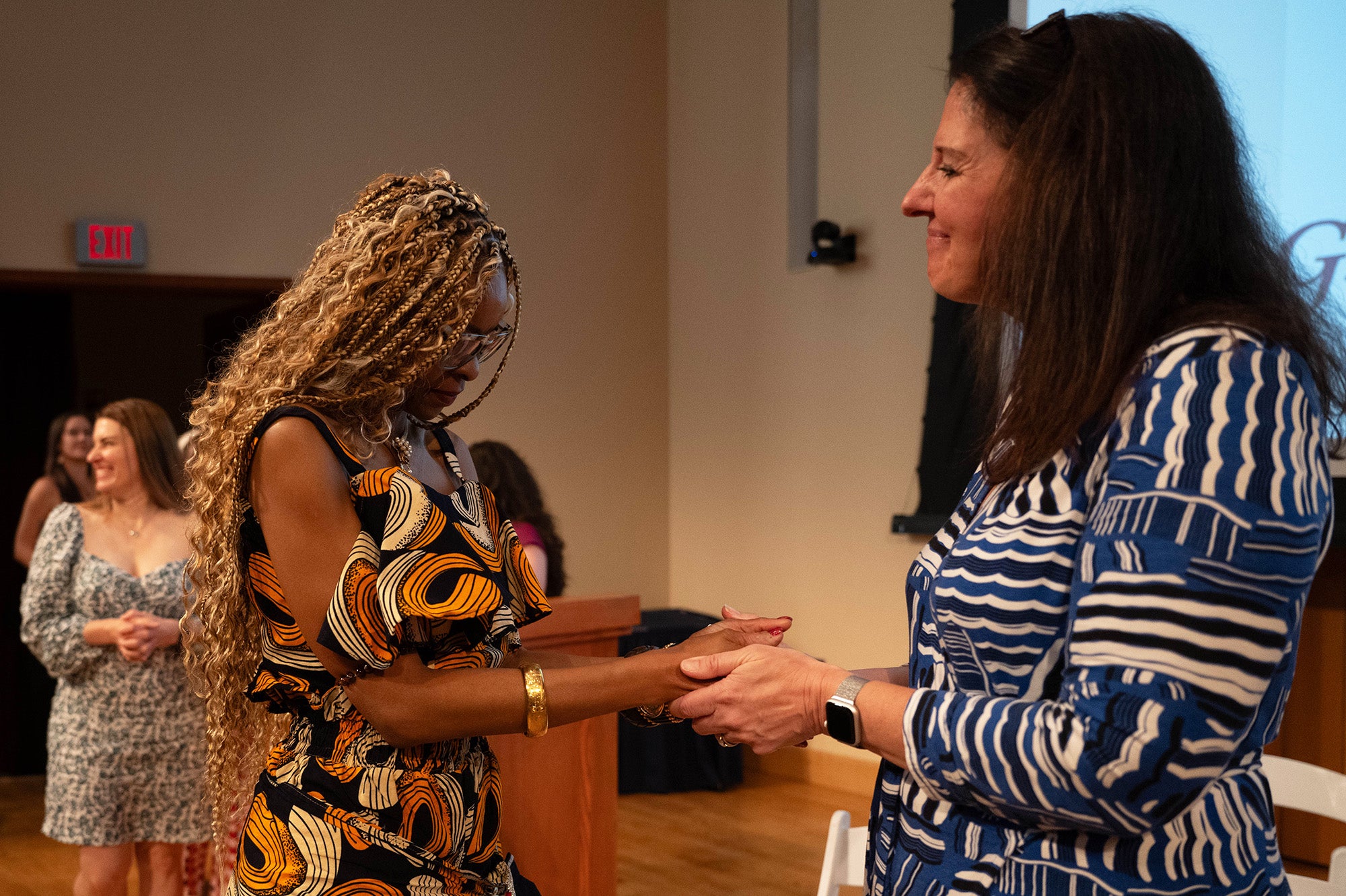 Heather Bradford holds the hands of Masimbit Kunje, who has bowed her head
