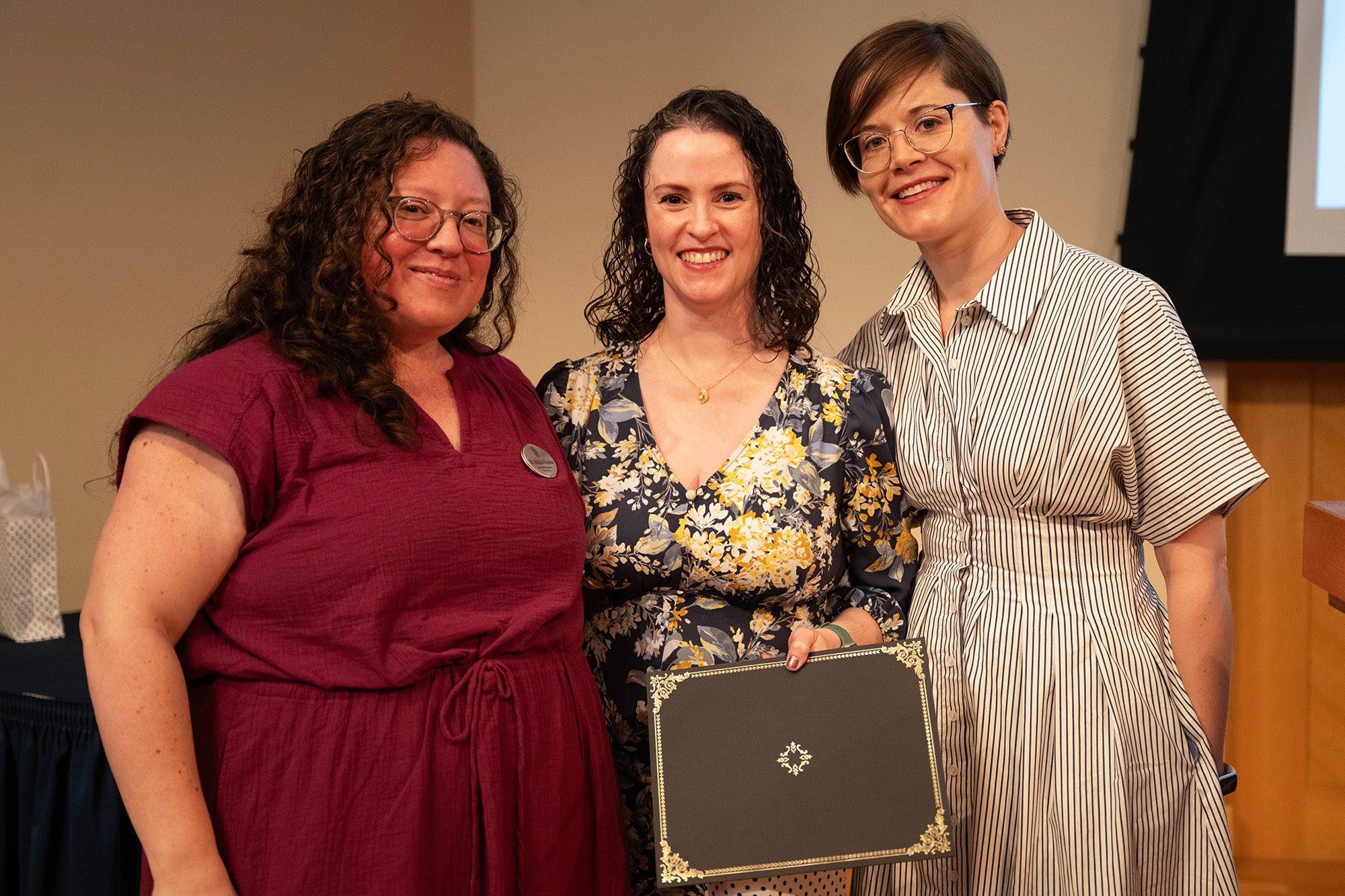 Melicia Escobar, Brittany Dowell and Katie Daily stand together as Dowell holds a brown leather case