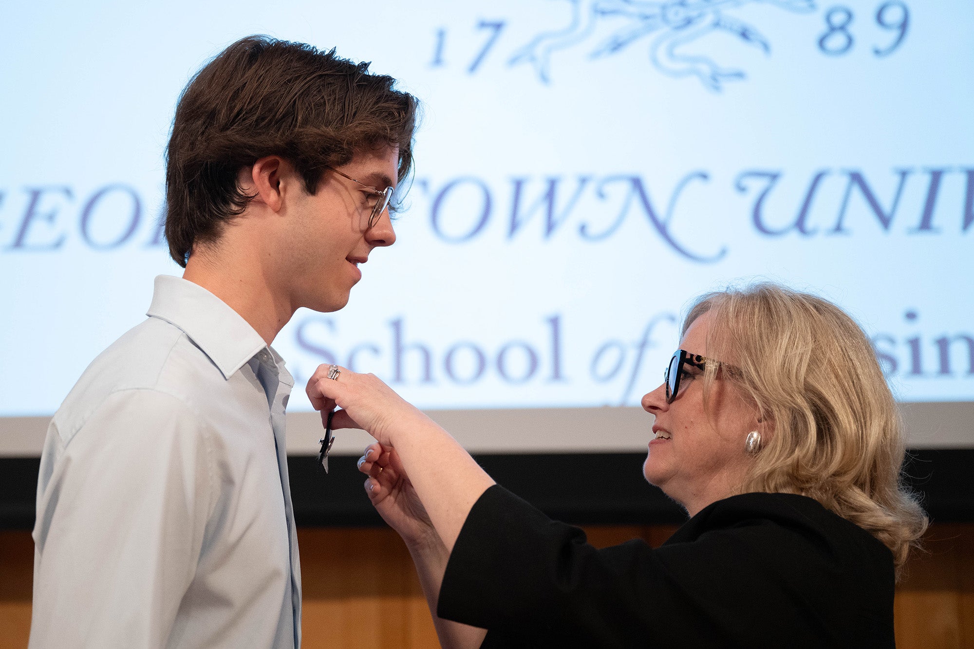 Luke Schrifels has a nursing pin pinned on his shirt by associate professor Sarah Vittone
