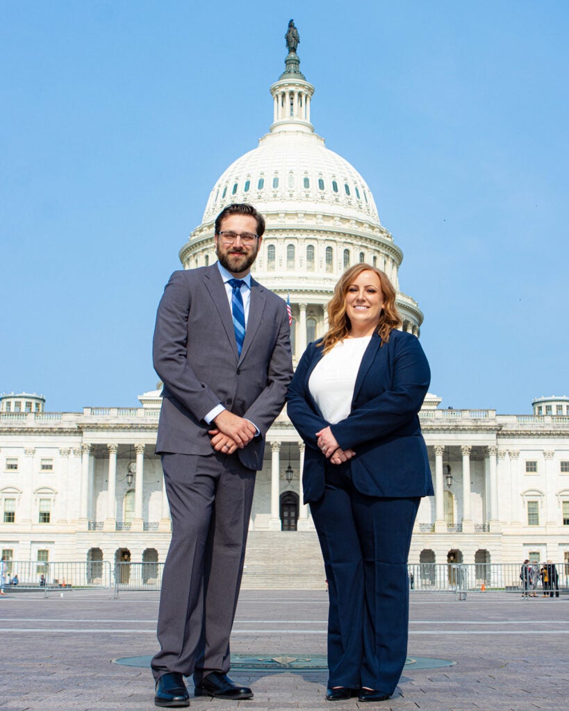 Two students stand together with the Capitol Building dome behind them