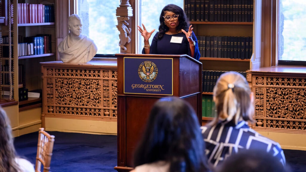 A woman speaks from behind a podium in Riggs Library