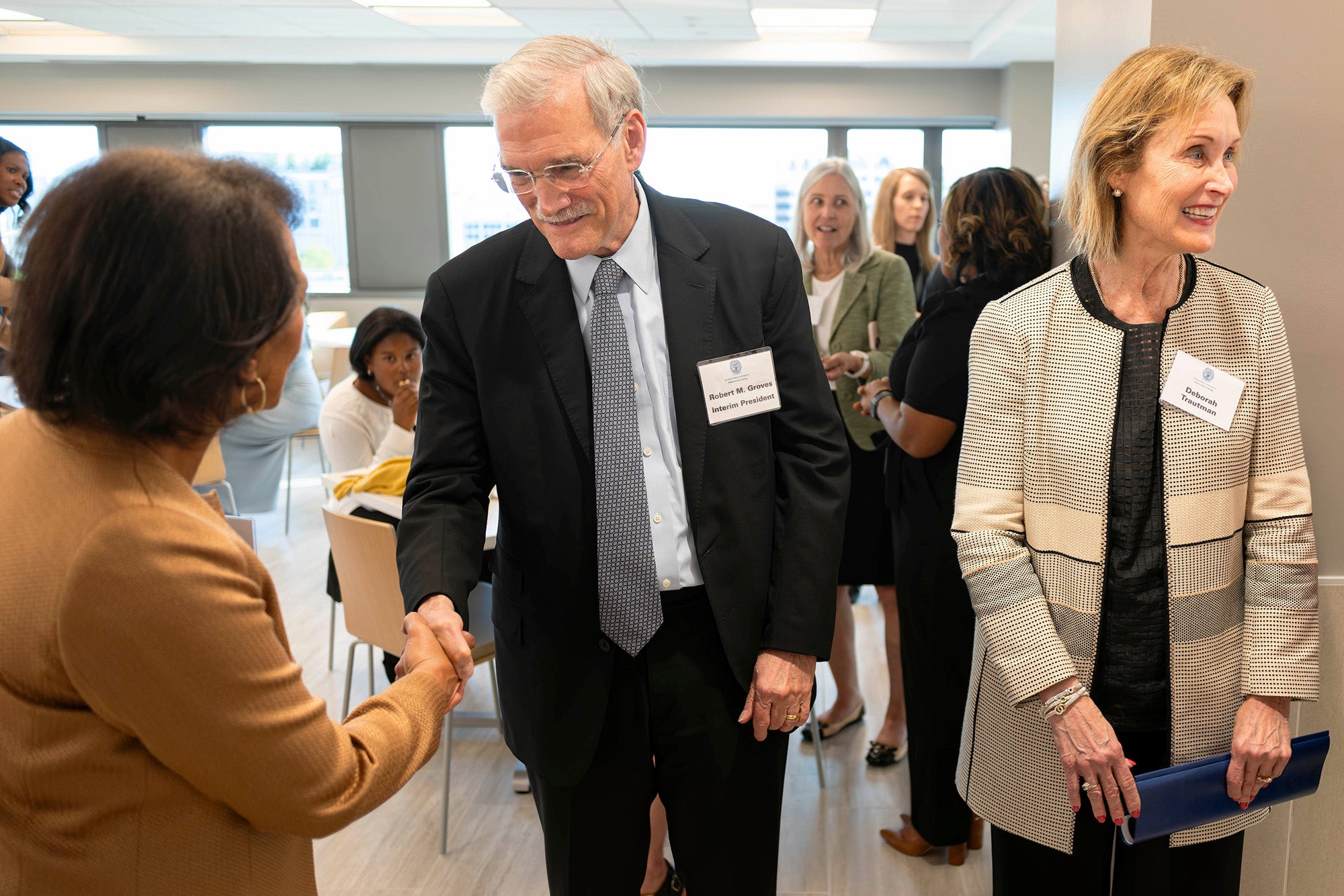 Interim president Groves shakes hands with Beverly Malone while Deb Trautman stands nearby