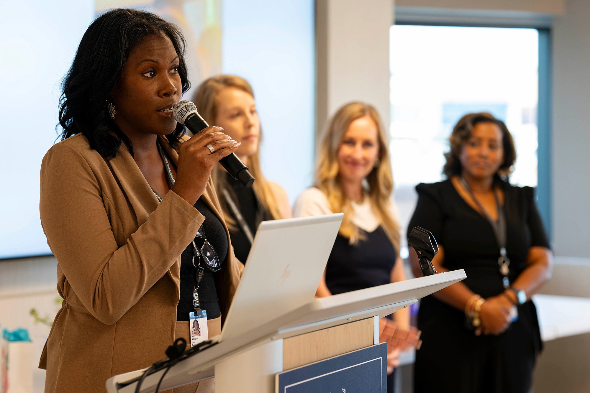 Jennifer Wallace speaks into a microphone while her three classmates stand in the background