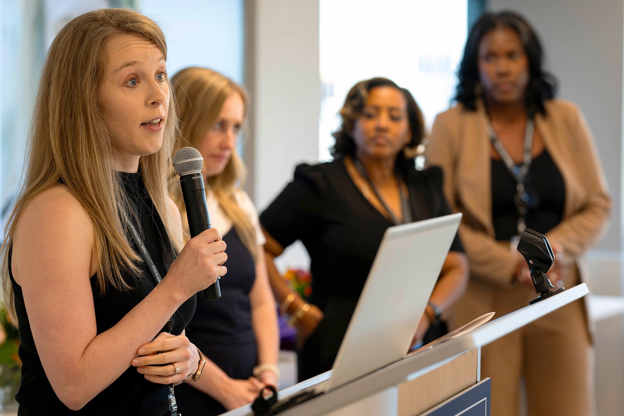 Sydney West speaks into a microphone while her three classmates stand in the background