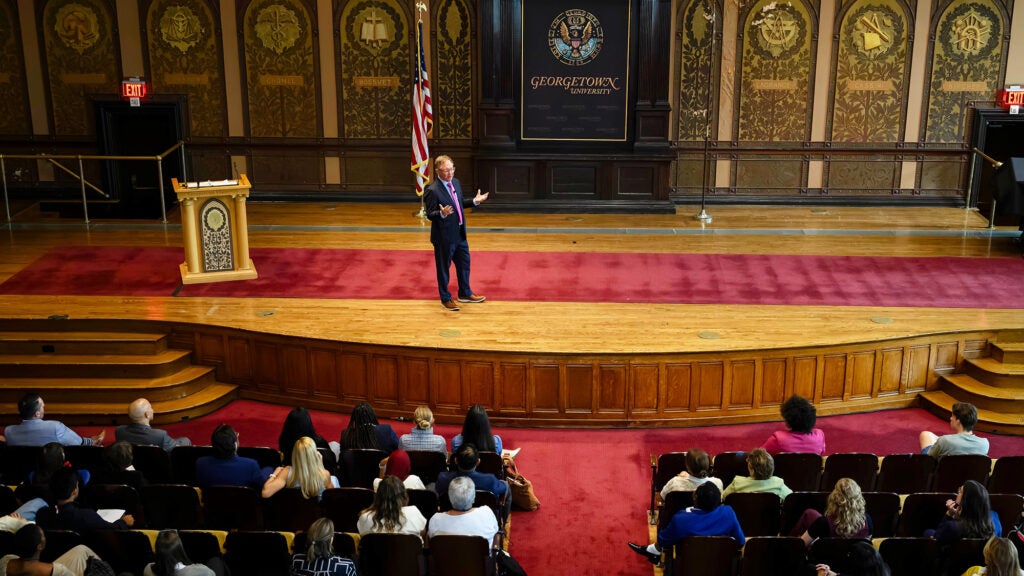 Quint Studer speaks onstage in Gaston Hall to an audience seated before him