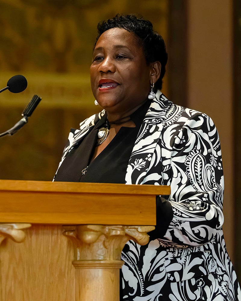 Roberta Waite speaks from a podium onstage in Gaston Hall