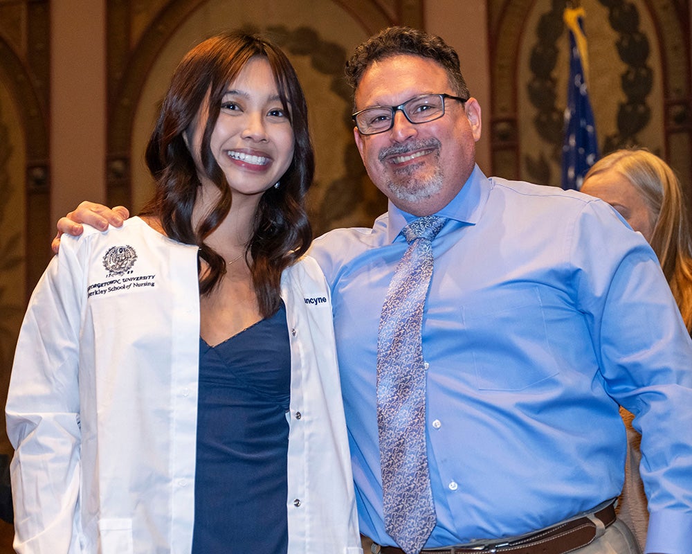 Francyne Diola, wearing her new white coat, stands next to Jeremy Sabatino