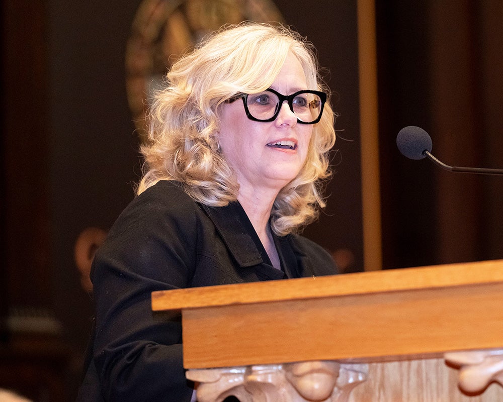 Sarah Vittone speaks from a podium during the White Coat ceremony