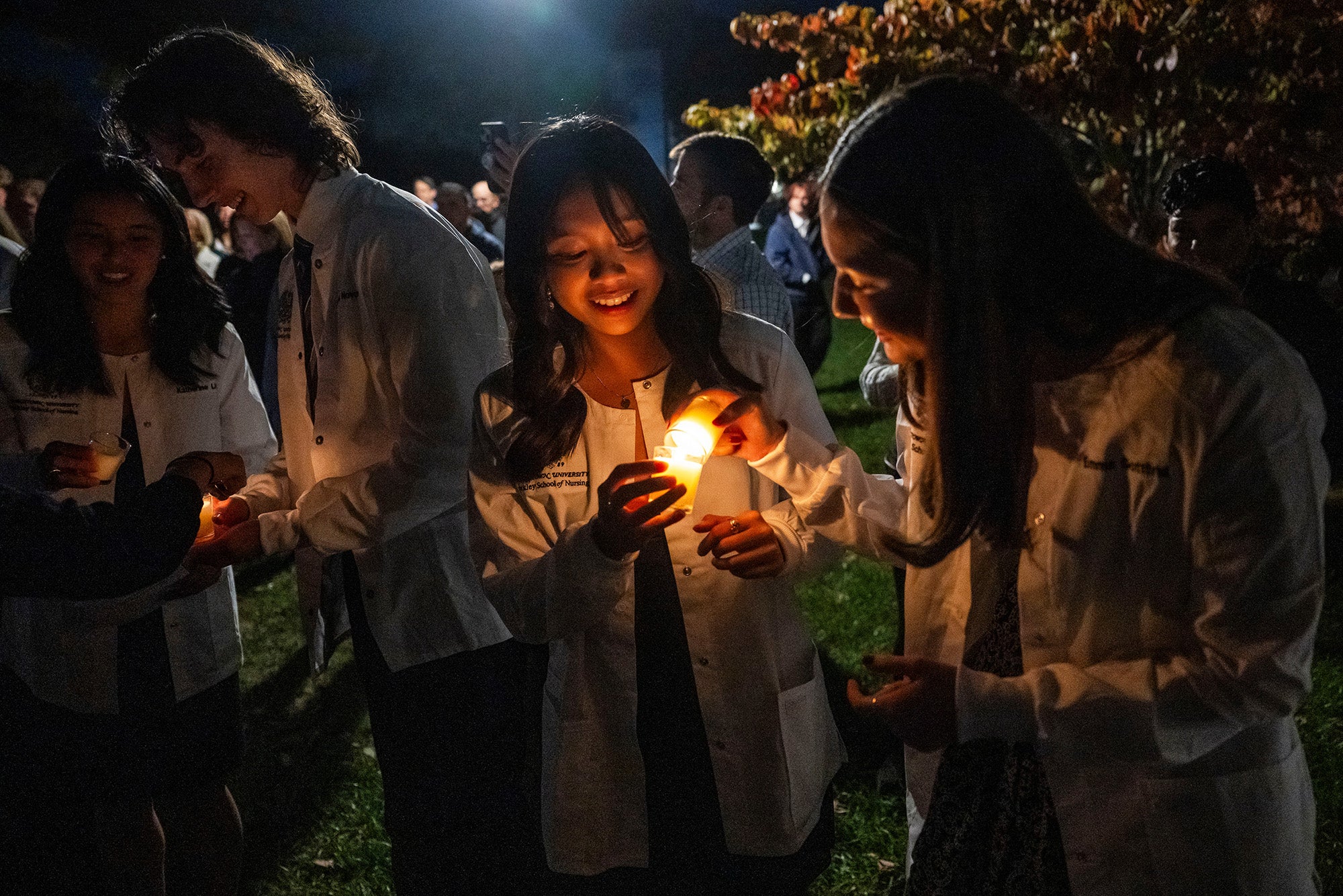 Students light candles during the outdoor portion of the ceremony