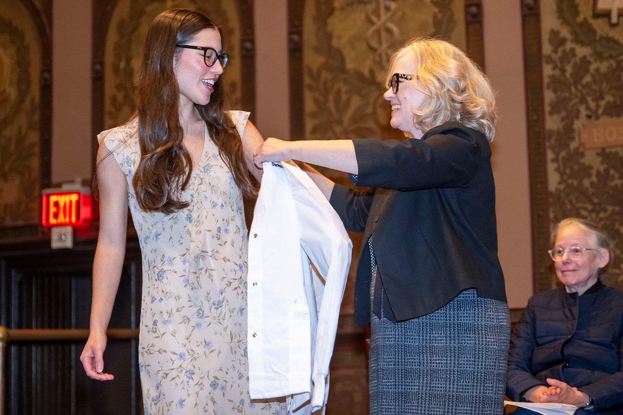 Sarah Vittone helps a student into her white coat