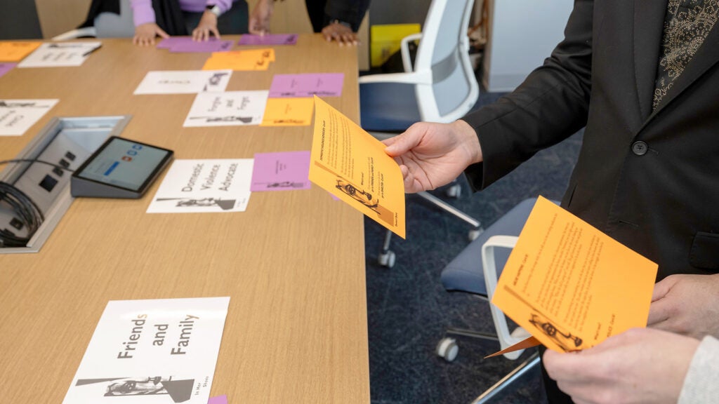A tabletop is arrayed with colorful cards printed with different scenarios for students to work through