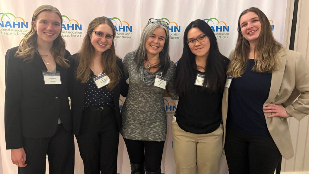 Four students flank professor Mirabal-Beltran in a group