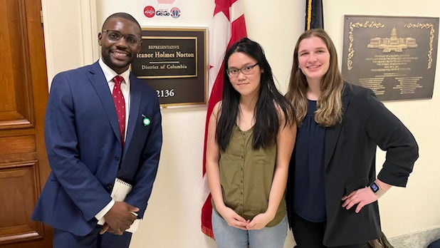 Two students stand in a hallway with a congressional staffer