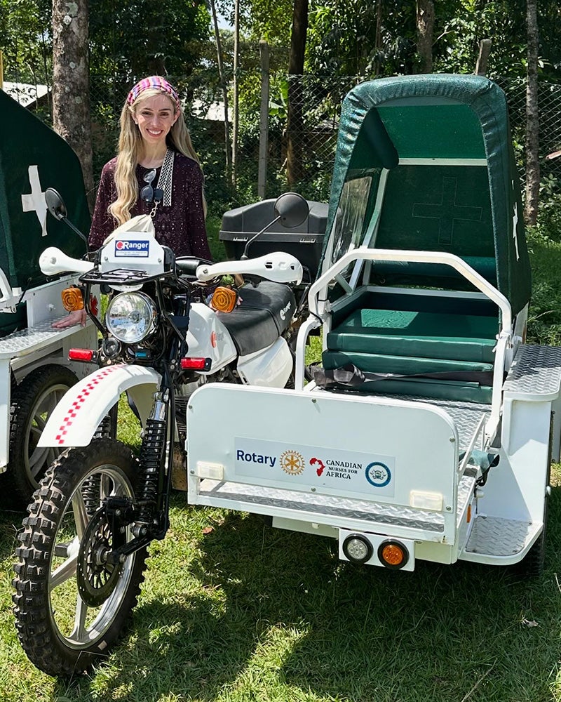 Alex stands next to an ambulance motocycle outfitted with covered sidecar