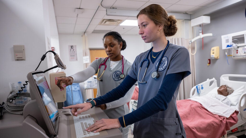 Two ABSN students consult a computer in the SIM lab