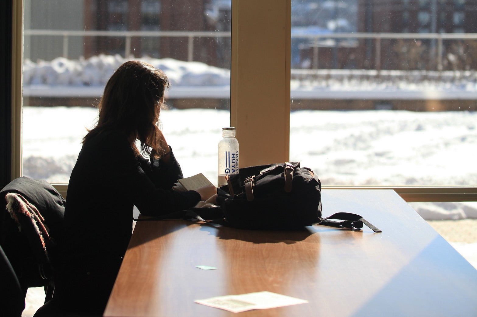 A student looks out a window at the snow outside