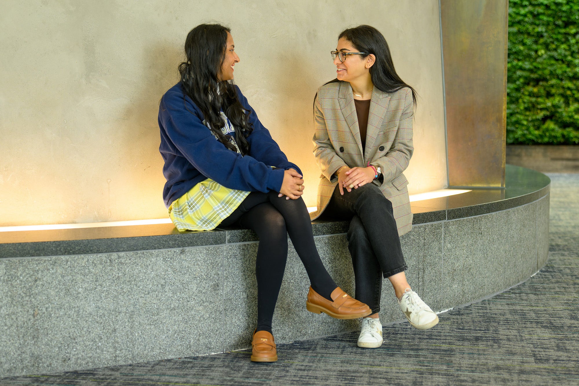 Two individuals speak face to face while seated