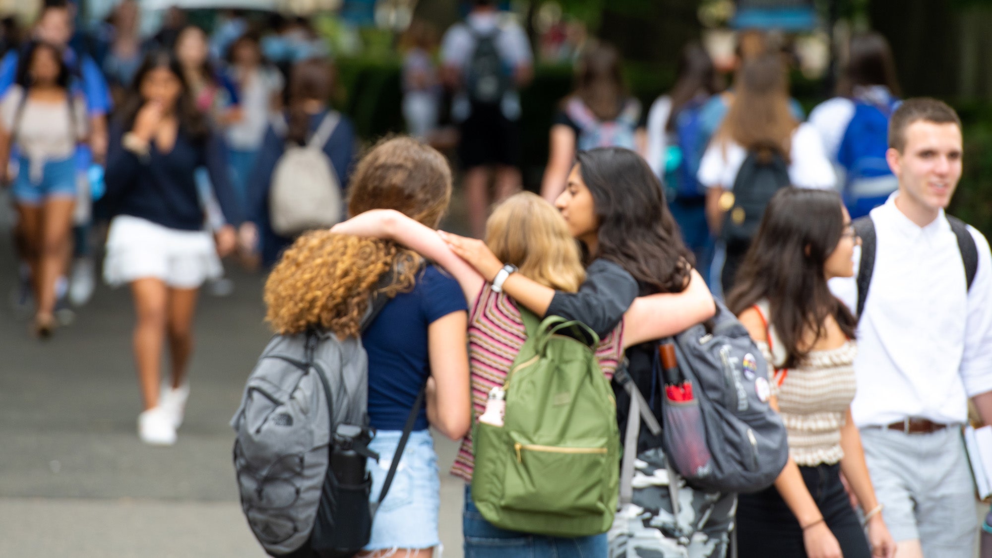 Three students link arms in a show of emotional support