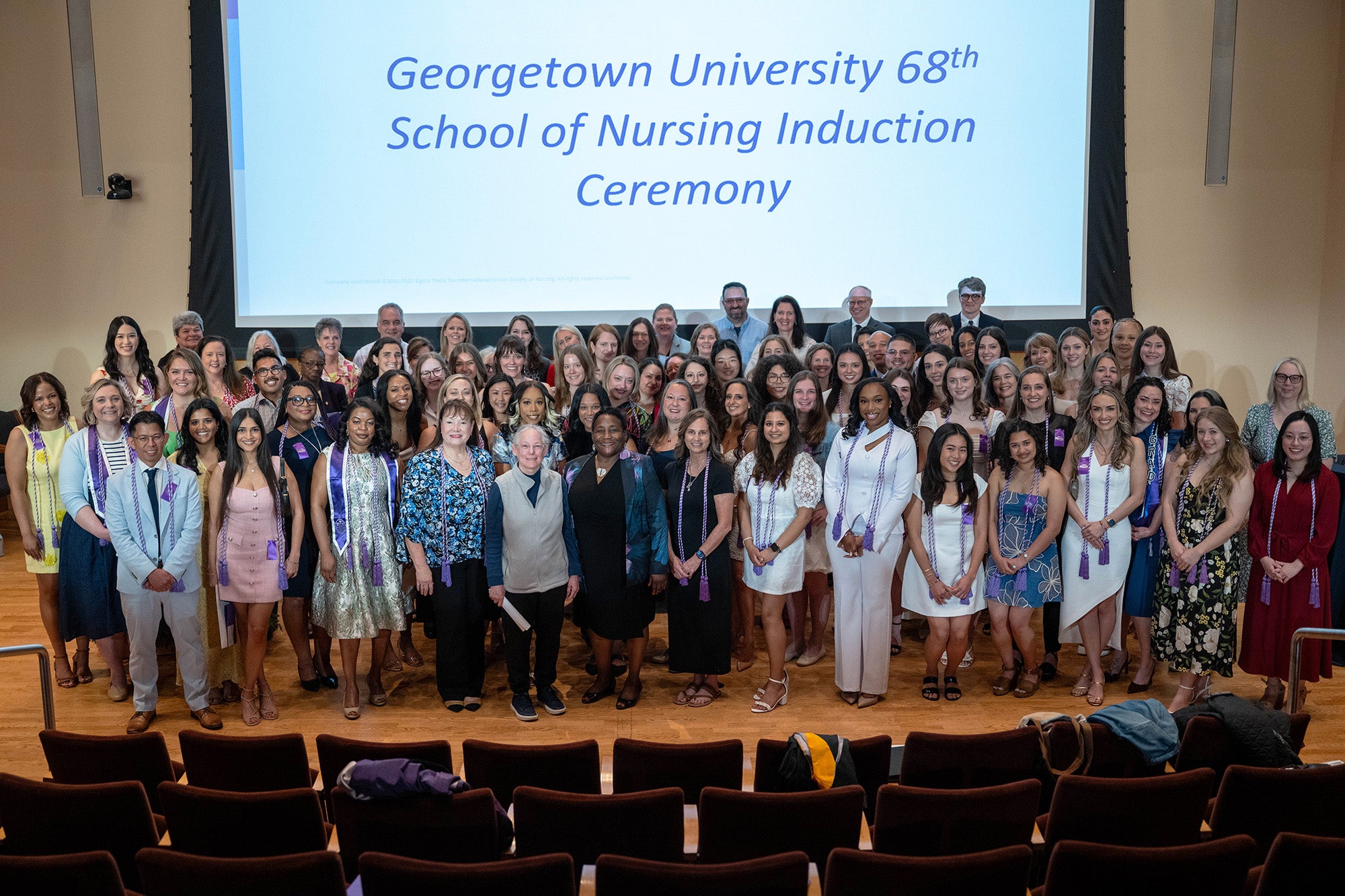 A large group of Sigma Theta Tau honorees stand together on a stage