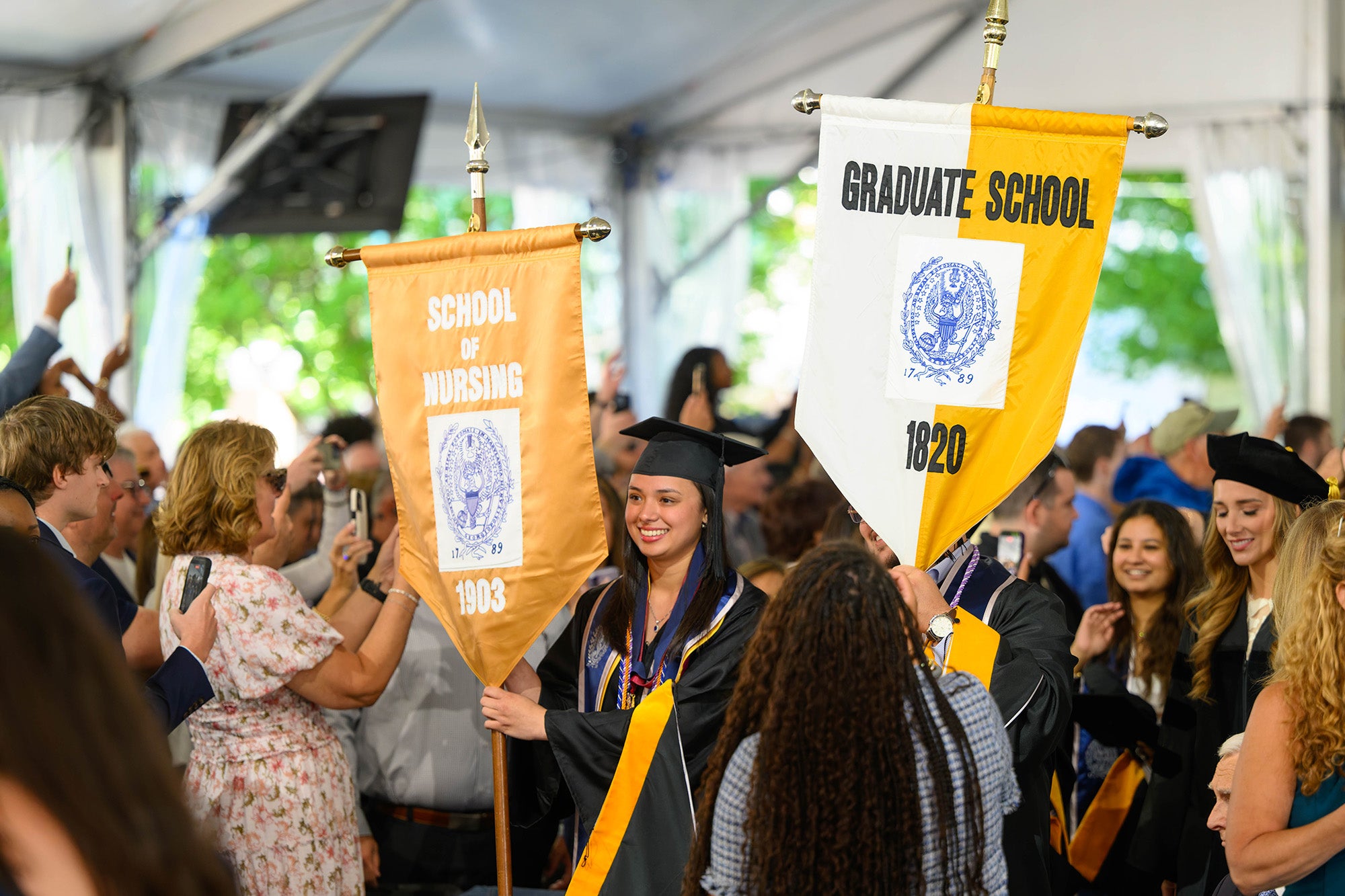 Students process into the ceremony behind two school banners