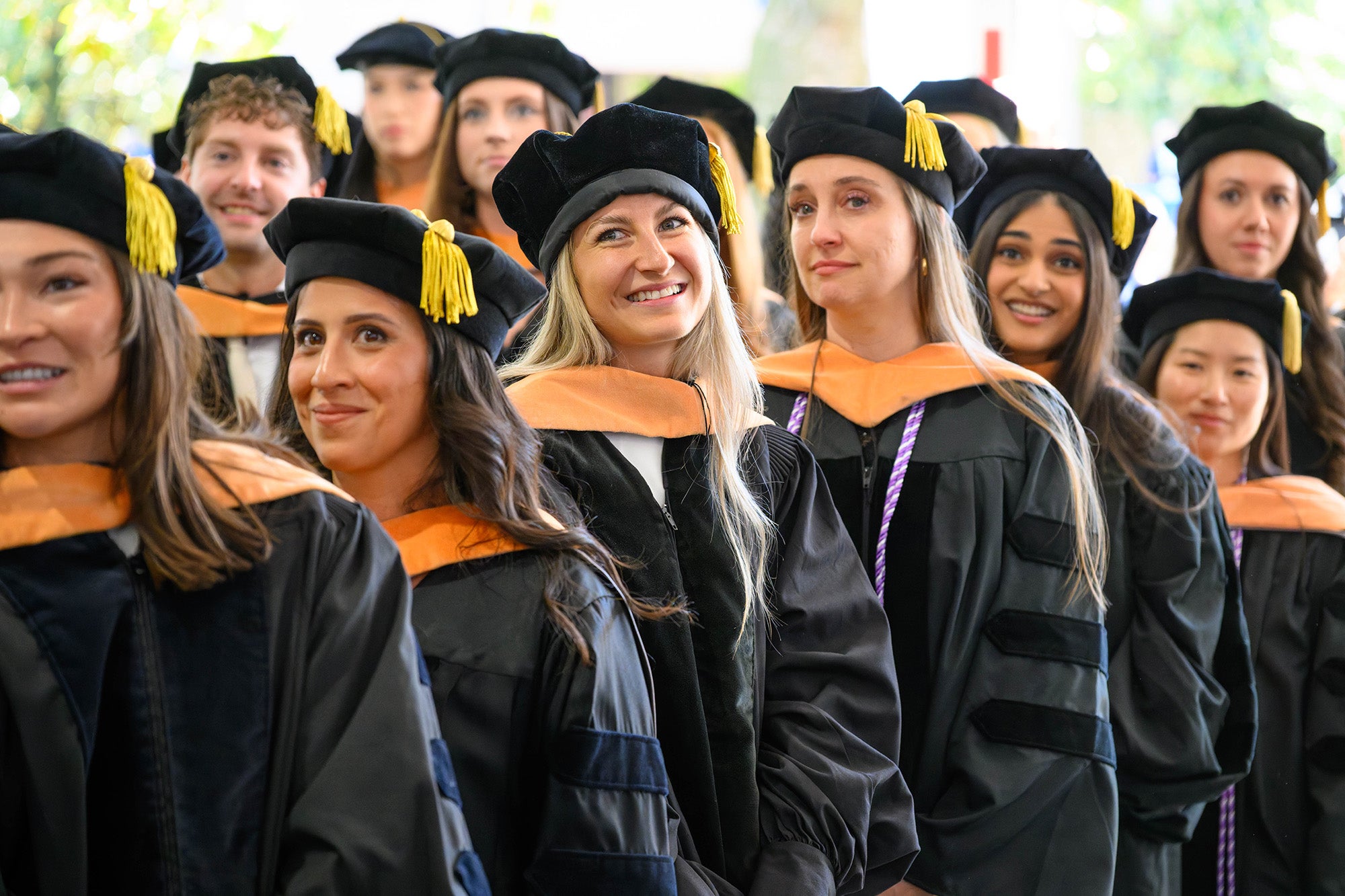 Students in caps and gowns stand in line at Commencement