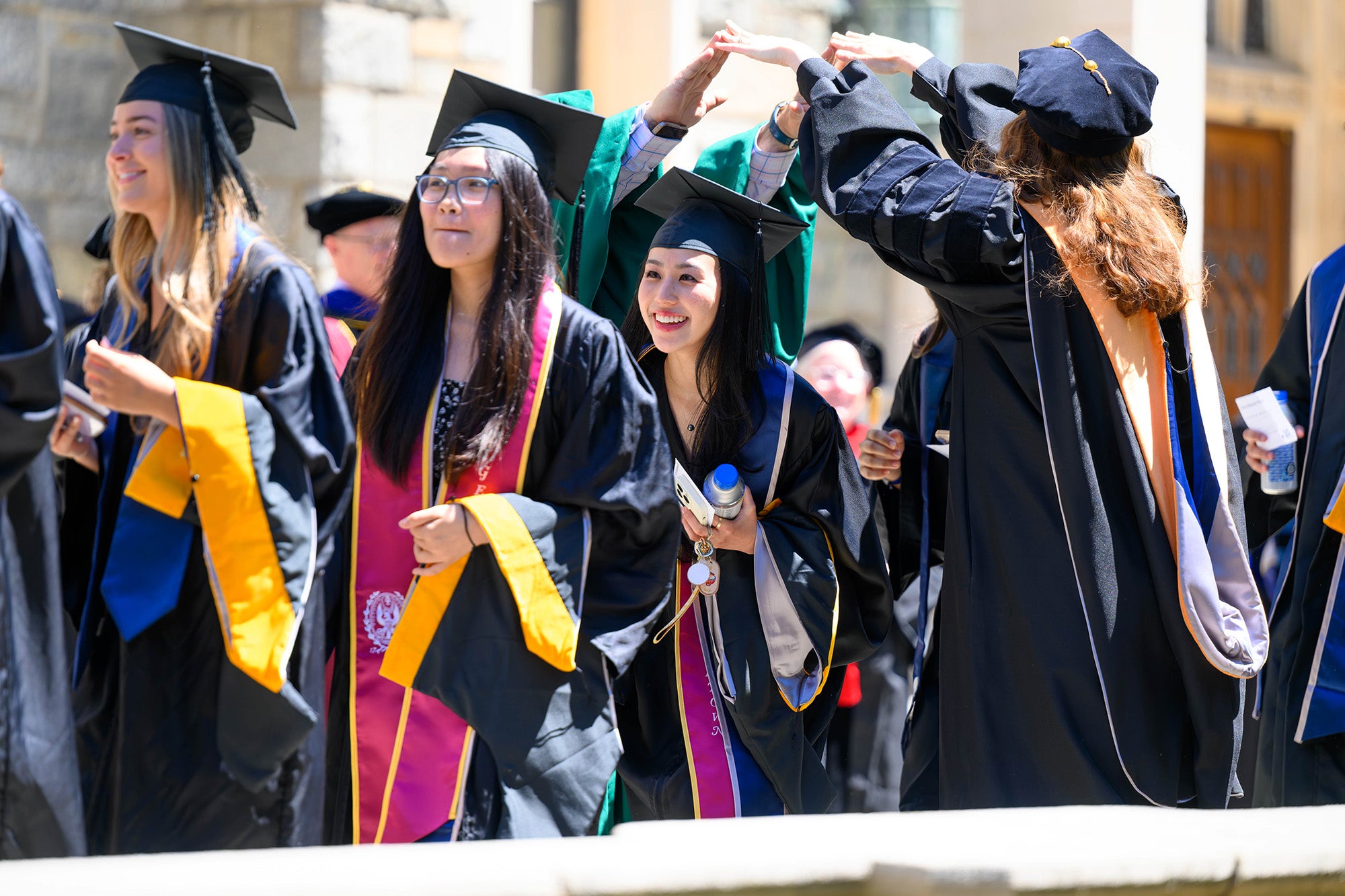 Students walk across campus in caps and gowns