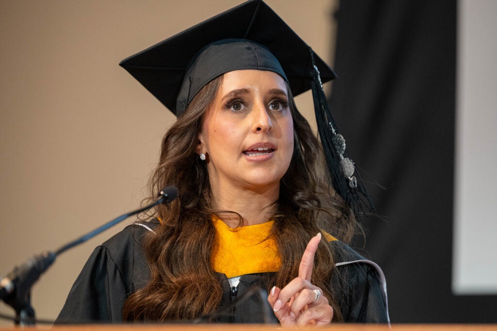 Joanna Ranelli speaks from a podium in cap and gown