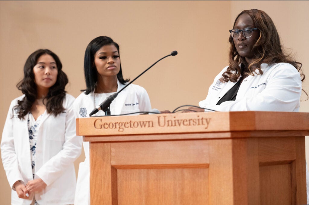 Three students stand together near a podium