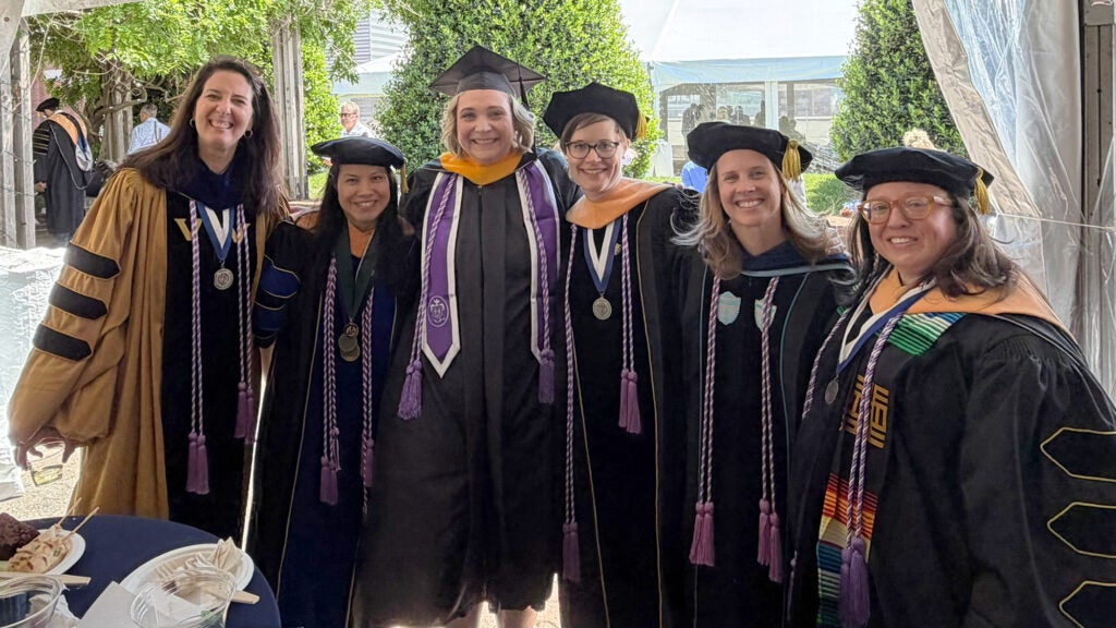 Five nursing faculty members stand with Becca Levy all dressed in academic regalia