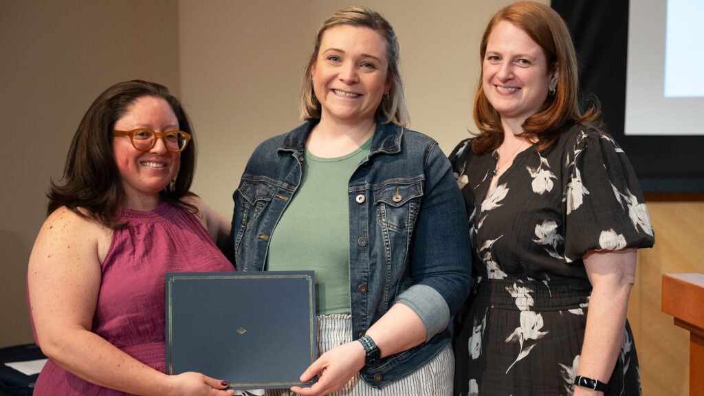 Becca Levy accepts an award at Tropaia from professors Melicia Escobar and  Ella Heitzler