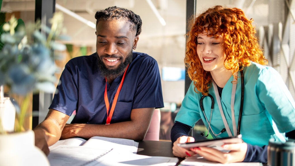 Two nursing or health students look at a notebook together